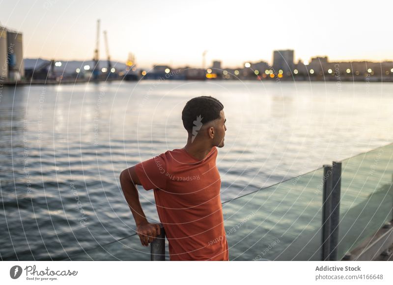 Ethnic tourist near ocean hand behind head enjoy vacation seascape sky summer twilight man traveler ethnic sunset water evening scenic idyllic horizon building