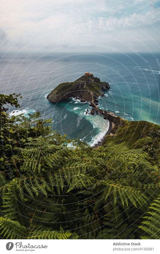 Rippled ocean near green mountain with walkway under sky gaztelugatxe nature highland san juan seascape atmosphere route landscape vegetate summer colorful