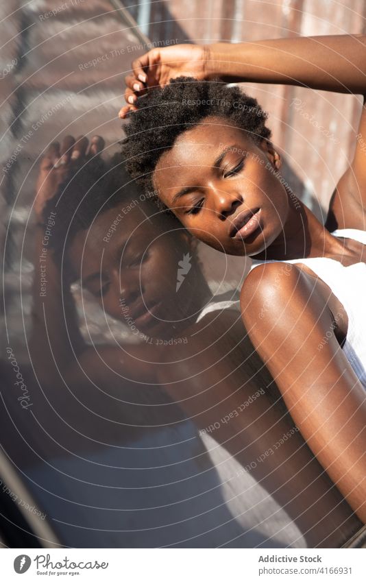 Relaxed black female model leaning on roof construction woman seductive eyes closed rooftop pose allure grace touch head feminine personality gorgeous confident