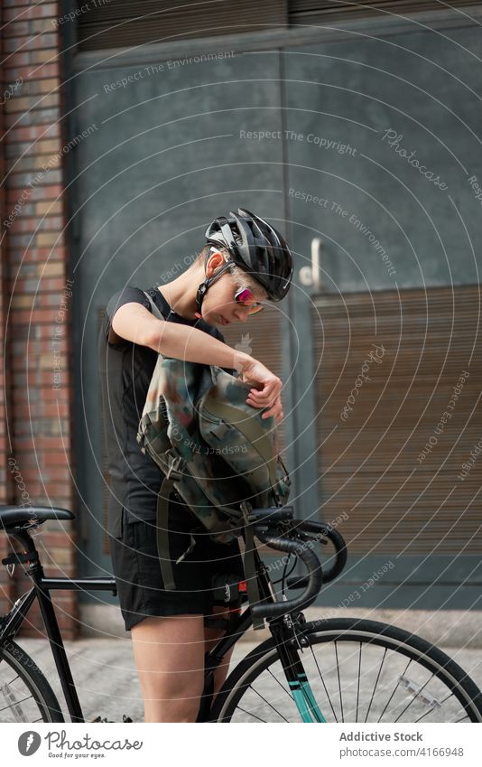 Woman cyclist on background of brick building , side view Cyclist bricked city day woman young sports riding summer helmet protective sunglasses girl delivery