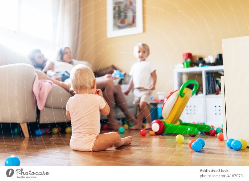 Infant resting in bright room with parents and sibling infant family play living room childhood baby children weekend innocent toddler boy diaper brother kid