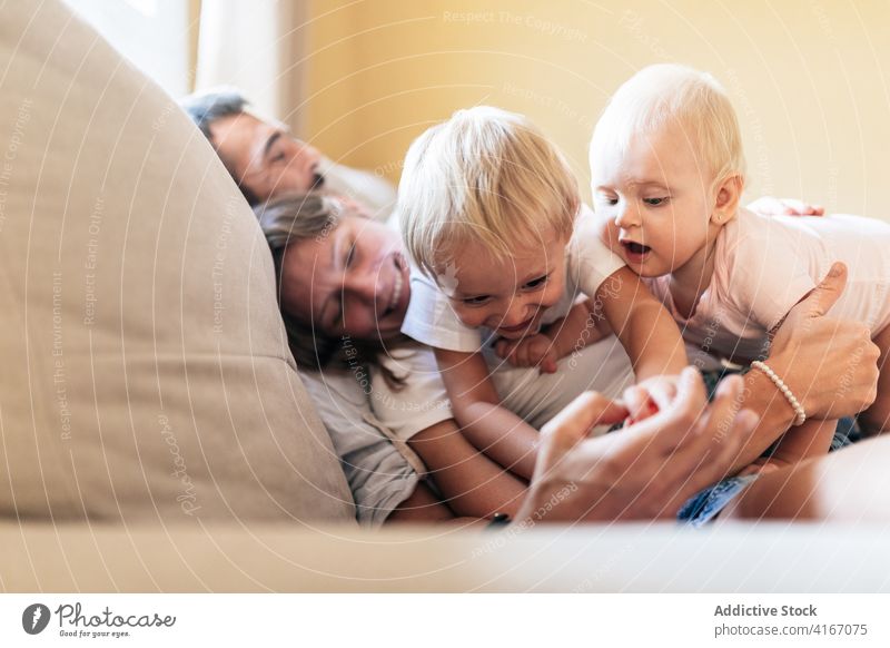 Happy family in bright cozy living room children cuddle bonding comfort couch toddler kid father mother together free time childhood rest lifestyle cheerful