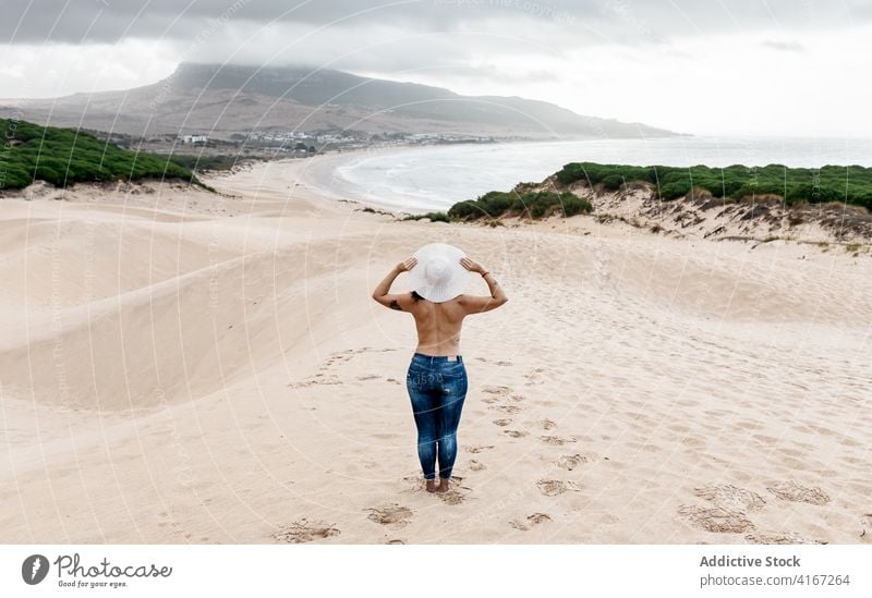 Unrecognizable shirtless female standing on sandy coastline woman topless seashore beach amazing tranquil waterfront paradise lifestyle picturesque journey