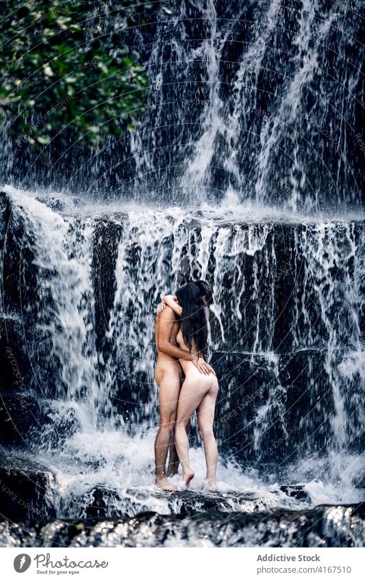 Naked couple hugging near waterfall naked nude vacation together erotic embrace tender summer romantic love relationship intimate nature girlfriend harmony