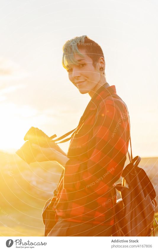 Photographer on hill at sunset travel photographer woman traveler photo camera explore adventure androgynous female alternative gender professional nature area