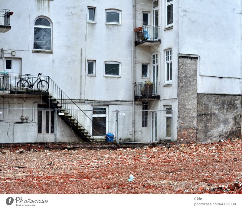 Debris of a demolished house in front of the windows of an old building outline rubbish Backyard Construction site Old building Destruction Bicycle bricks