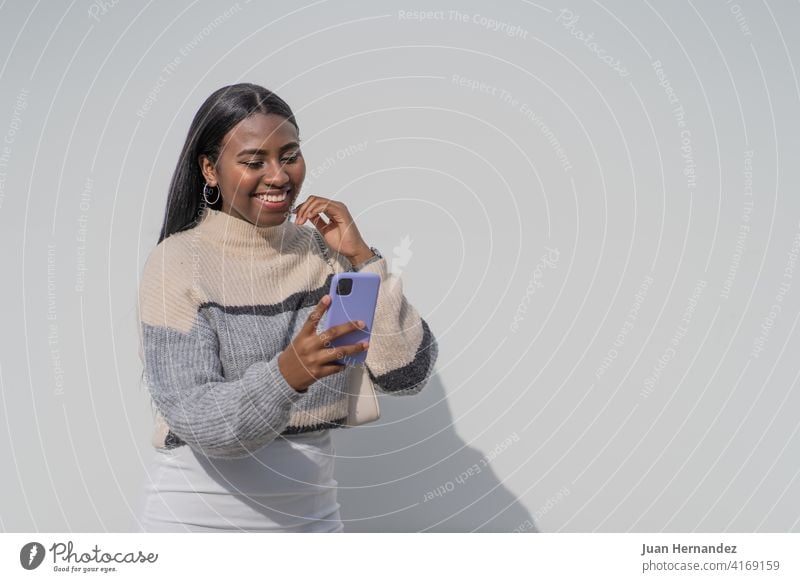 Young black woman with a purple smartphone pretty young african cellphone afro african american young adult mobile phone message internet horizontal smile happy