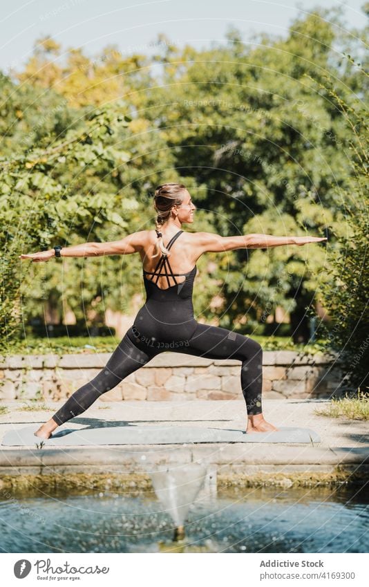 Woman balancing in warrior yoga pose in park woman tree virabhadrasana balance stand practice position fit female wellness slim posture energy wellbeing harmony