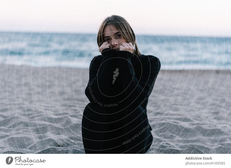 Peaceful woman on seashore in evening tender beach twilight sunset enjoy warm sweater female young relax calm ocean sand sundown freedom sit water coast rest