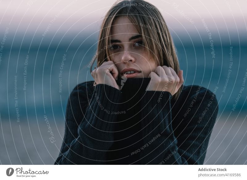 Peaceful woman on seashore in evening tender beach twilight sunset enjoy warm sweater female young relax calm ocean sand sundown freedom sit water coast rest