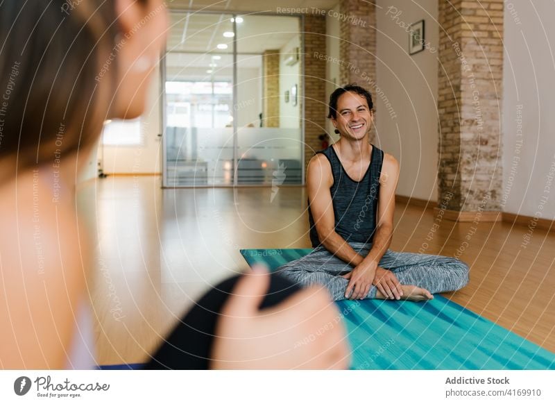 Man smiling chatting in yoga studio man speak lesson smile person break group mat talk cheerful relax conversation rest joy friend happy communicate healthy sit