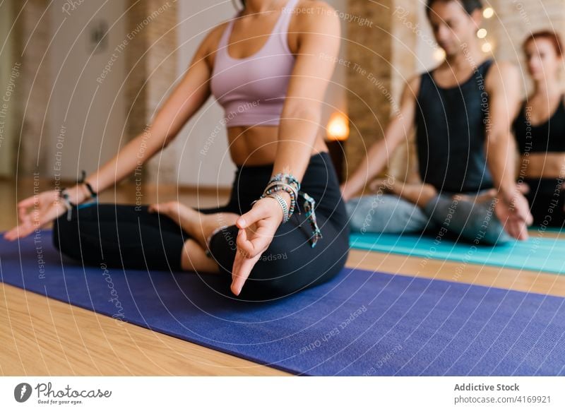 Crop woman meditating with group in studio meditate yoga lesson lotus pose mat mindfulness zen female wellness serene balance spirit wellbeing practice healthy