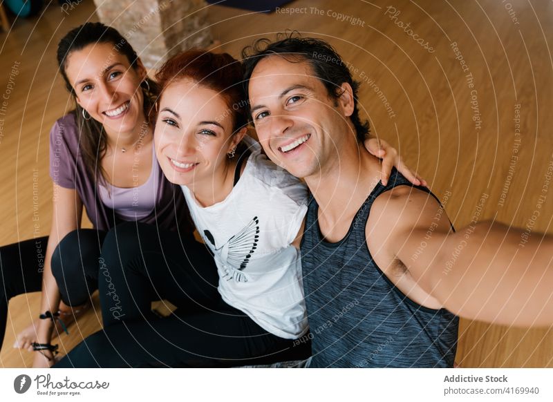 People taking selfie during yoga lesson man women together studio smile smartphone hug break group happy cheerful relax embrace rest gadget joy device optimist