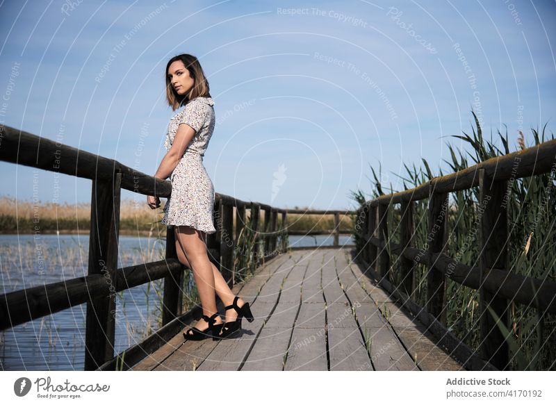 Woman standing on wooden bridge over lake woman boardwalk pier alone summer nature river water rest calm vacation tranquil countryside serene female lifestyle