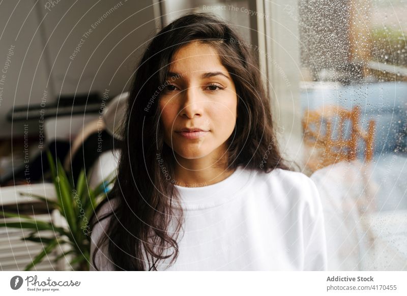 Peaceful woman standing at window with waterdrops raindrop melancholy mood droplet peaceful tranquil ethnic female tender calm solitude lonely alone gentle