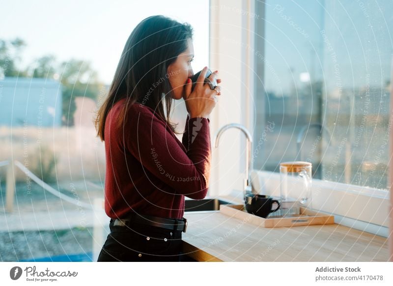 Tranquil woman drinking morning coffee in kitchen tranquil enjoy calm counter cup female serene beverage breakfast casual relax mug hot home peaceful modern