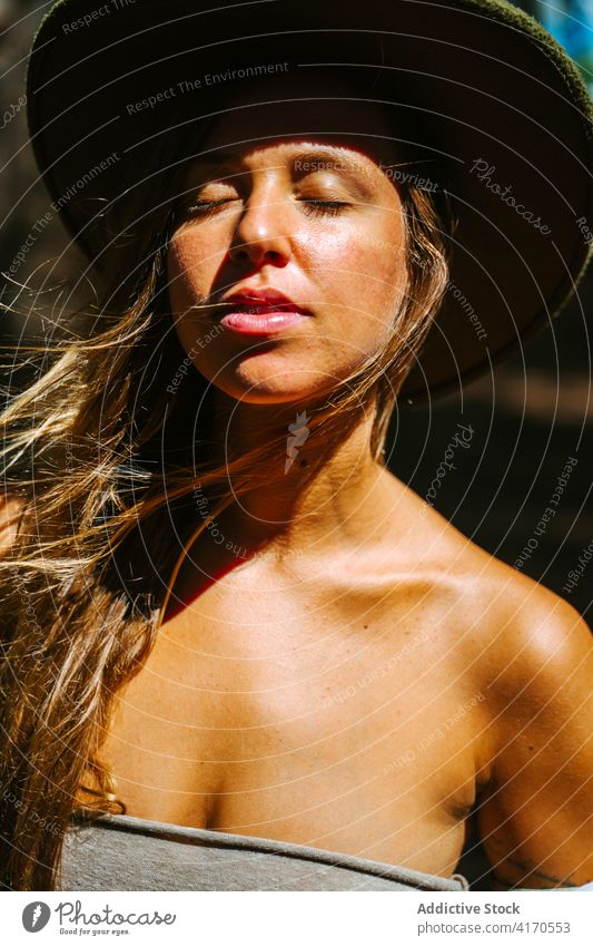 Carefree woman enjoying nature in forest carefree freedom eyes closed wind sunlight gentle hippie female hipster hat top peaceful woods summer serene young