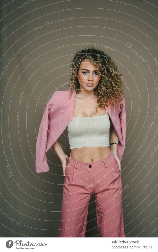 Fashionable woman in trendy outfit in studio apparel style curly hair afro hairstyle model female slim individuality contemporary cool cloth elegant jacket suit