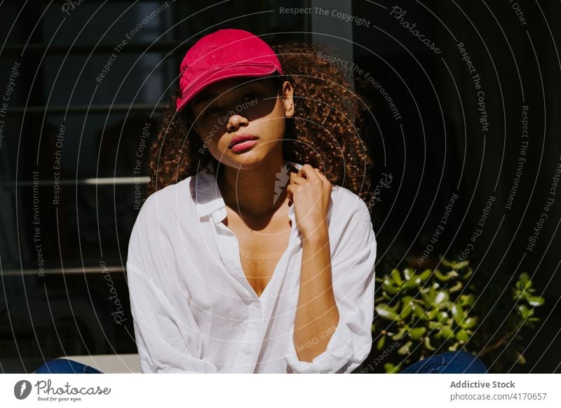 Tranquil ethnic woman sitting near window hair afro hairstyle relax tranquil sunlight calm young african american black female gorgeous hairdo curly hair