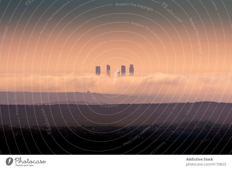 Skyscrapers above clouds in evening skyscraper skyline sunset cityscape cuatro torres business area thick cloudy high rise megalopolis madrid spain picturesque