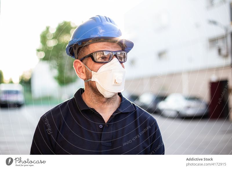 Workman in protective mask and glasses standing on street worker mechanic repairman respirator professional glove occupation male adult service lifestyle