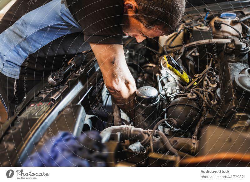 Technician with flashlight examining car motor man mechanic check engine garage illuminate work repair male vehicle transport service job fix busy technician