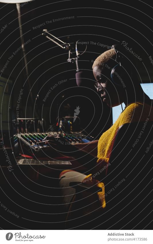 Ethnic woman speaking in microphone at radio station broadcast host on air live female ethnic black african american control panel studio dark work job talk