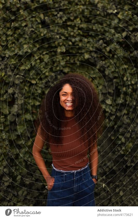 Happy ethnic woman in green garden charming smile natural beauty candid curly hair afro hairstyle park female black african american young happy cheerful joy