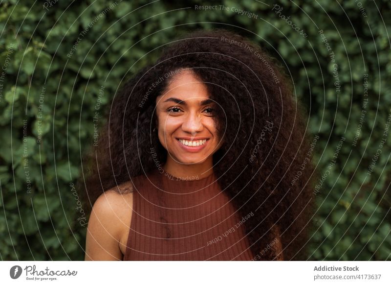 Happy ethnic woman in green garden charming smile natural beauty candid curly hair afro hairstyle park female black african american young happy cheerful joy