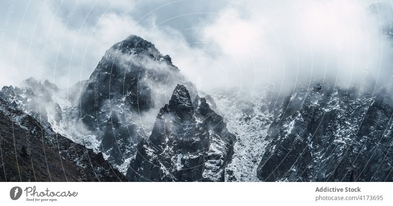 Rocky mountain ridge covered with snow rock range rough slope peak cloud panorama cold majestic scenery rocky nature landscape altitude environment picturesque