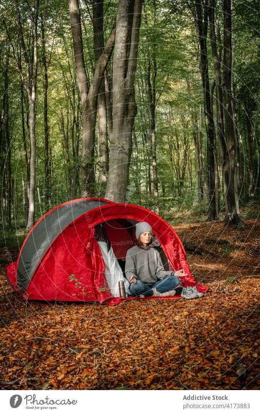 Woman meditating near tent in forest camp woman meditate yoga woods relax lotus pose traveler female zen serene spirit eyes closed padmasana tranquil calm