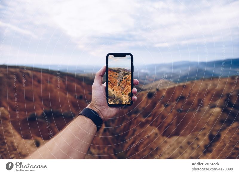 Traveler taking photo of mountains on smartphone traveler take photo erosion hand wild nature landscape male mobile gadget adventure device explore journey