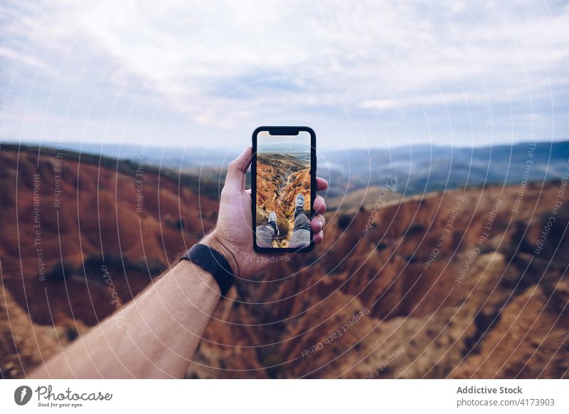 Traveler taking photo of mountains on smartphone traveler take photo erosion hand wild nature landscape male mobile gadget adventure device explore journey