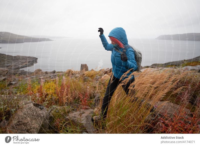 Traveling woman hiking in highlands near sea hike traveler trekking autumn rocky terrain explorer backpack cold female weather warm clothes fall hiker trip