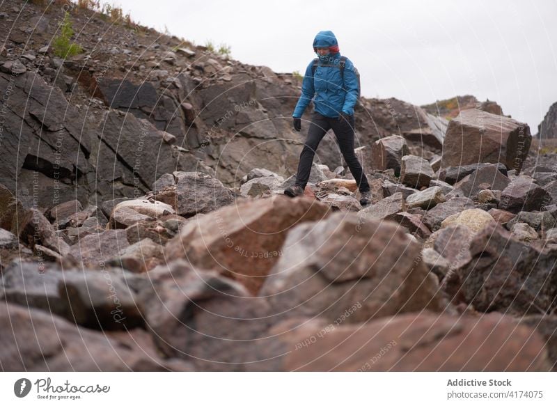 Traveling woman walking in rocky terrain during hiking trekking hike hiker explore autumn warm clothes female explorer travel nature rough cloudy vacation