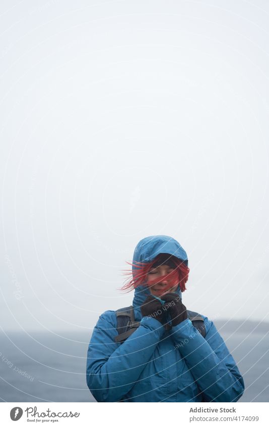 Traveler on hill near sea with closed eyes travel adventure wanderlust viewpoint observe cloudy autumn explorer backpack rocky nature journey tourism amazing