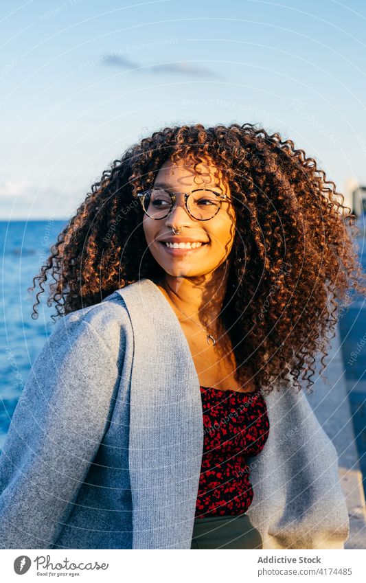 Cheerful black female sitting on embankment woman sea smile style weekend happy outfit rest young quay cheerful ethnic african american water delight relax