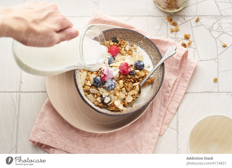 Breakfast with granola, berries and milk breakfast food healthy hand pouring organic cereal fruit muesli berry bowl grain diet flake snack yogurt fresh natural