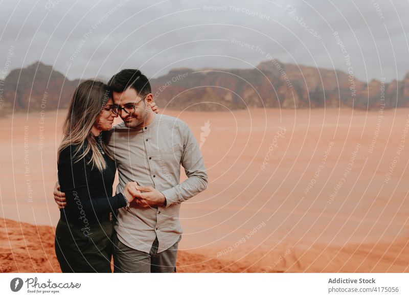 Loving couple of tourists hugging in desert traveler sandstone valley together tender vacation enjoy wadi rum jordan adventure happy tourism embrace love