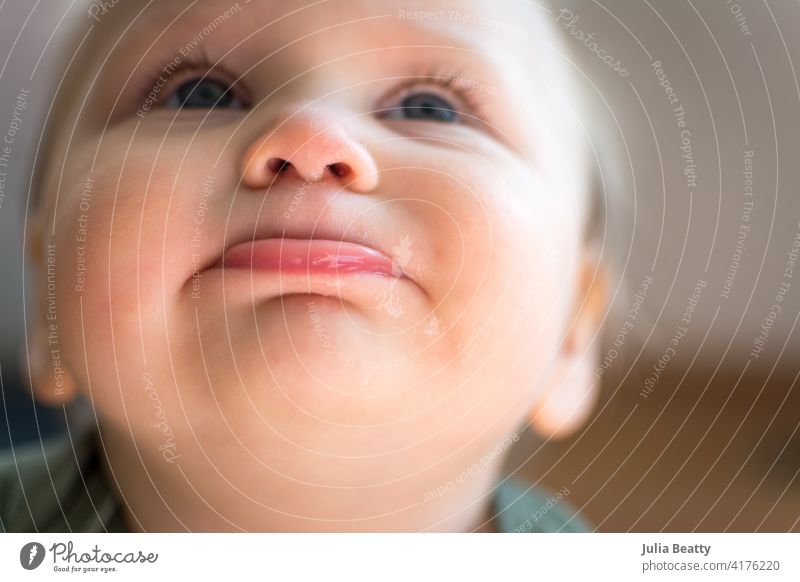 Looking up at the face of cute chubby toddler; bottom lip pushed out and eyes looking skyward baby child portrait lips nostril eye lashes teething drool