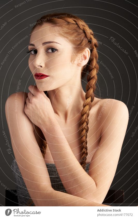 Woman with braids in studio looking at camera redhead hairstyle woman appearance charming trendy red hair female red lips model personality individuality