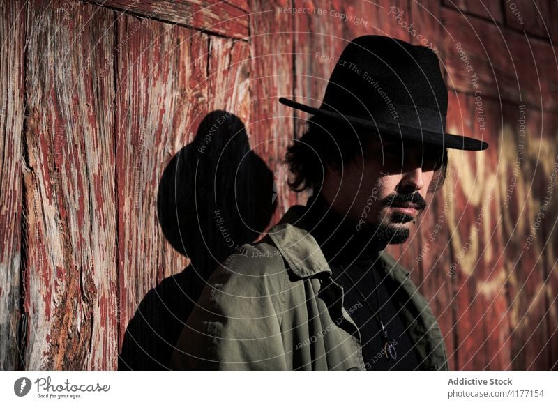 Hipster traveler in hat standing near old building man hipster style weathered countryside shabby trendy rural male young put on headwear headgear journey guy