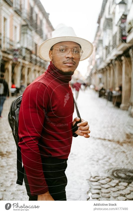 Ethnic man in stylish outfit walking along street style hat city confident trendy backpack male ethnic black african american stroll urban modern young