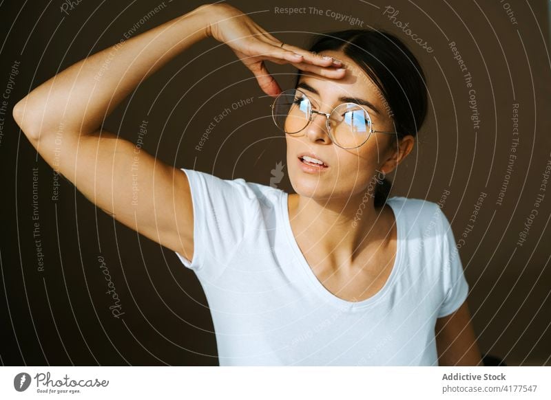 Young woman touching forehead and looking away thoughtful casual outfit peaceful white t shirt studio charming pensive female calm style ponder stand