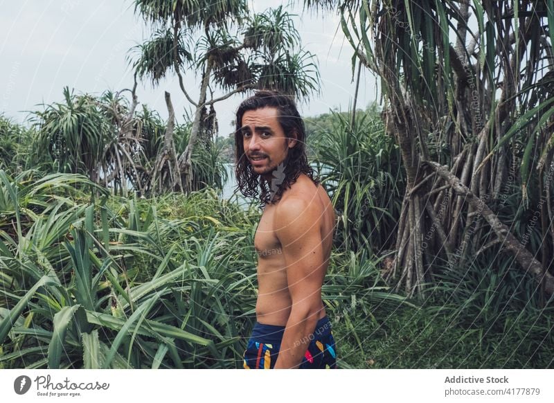 Shirtless ethnic man standing in jungle sea tropical exotic nature shirtless traveler male tourism bay sri lanka hiriketiya journey green coast shore lifestyle