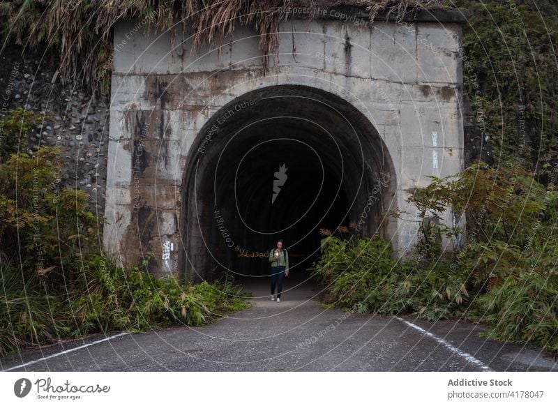 Traveler walking through arched tunnel traveler road passage weathered stone way narrow path route tourism building construction architecture aged roadway