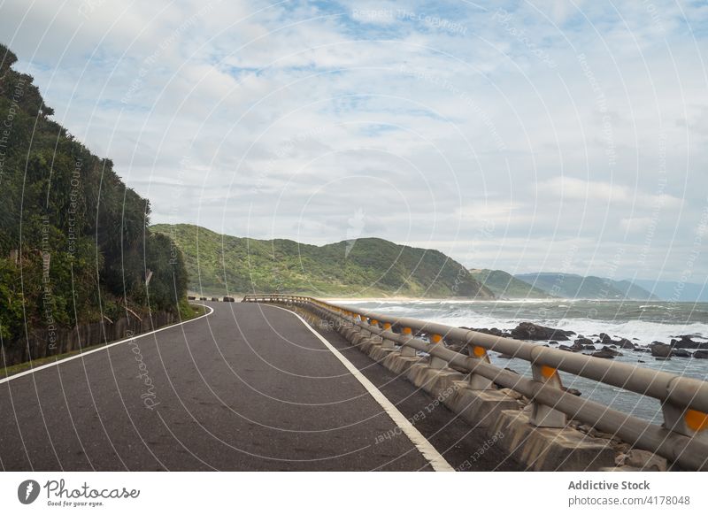 Asphalt road along sea in mountainous area roadway scenery amazing picturesque empty asphalt sunny east coast route direction destination location season