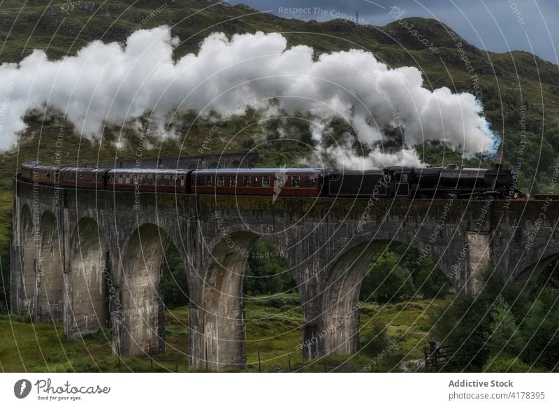 Steam train riding along railway viaduct glenfinnan viaduct steam landmark famous railroad mountain scotland united kingdom uk cloudy destination sky scenic