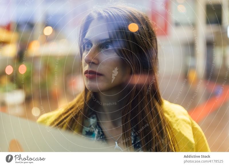 Pensive young woman looking through glass shop window positive urban showcase modern optimist female street lifestyle human face lady enjoy customer charismatic