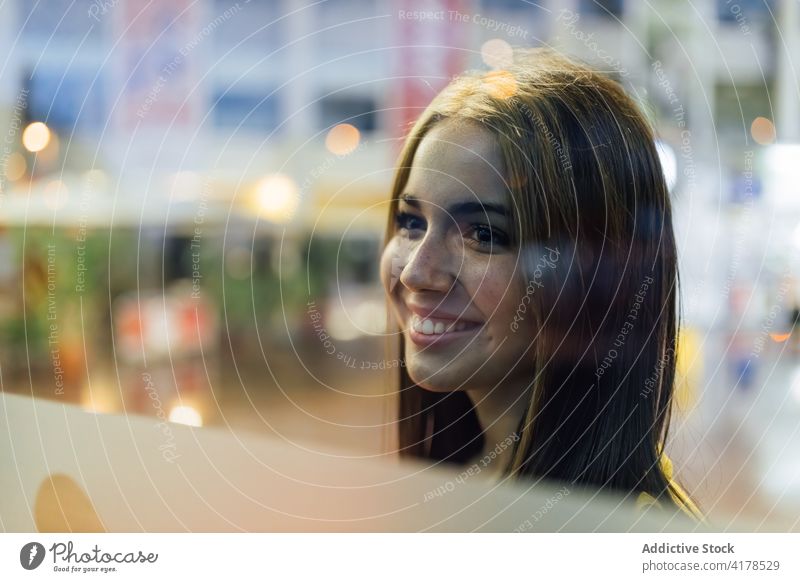 Cheerful young woman looking through glass shop window cheerful positive smile urban showcase happy modern optimist female street lifestyle human face lady